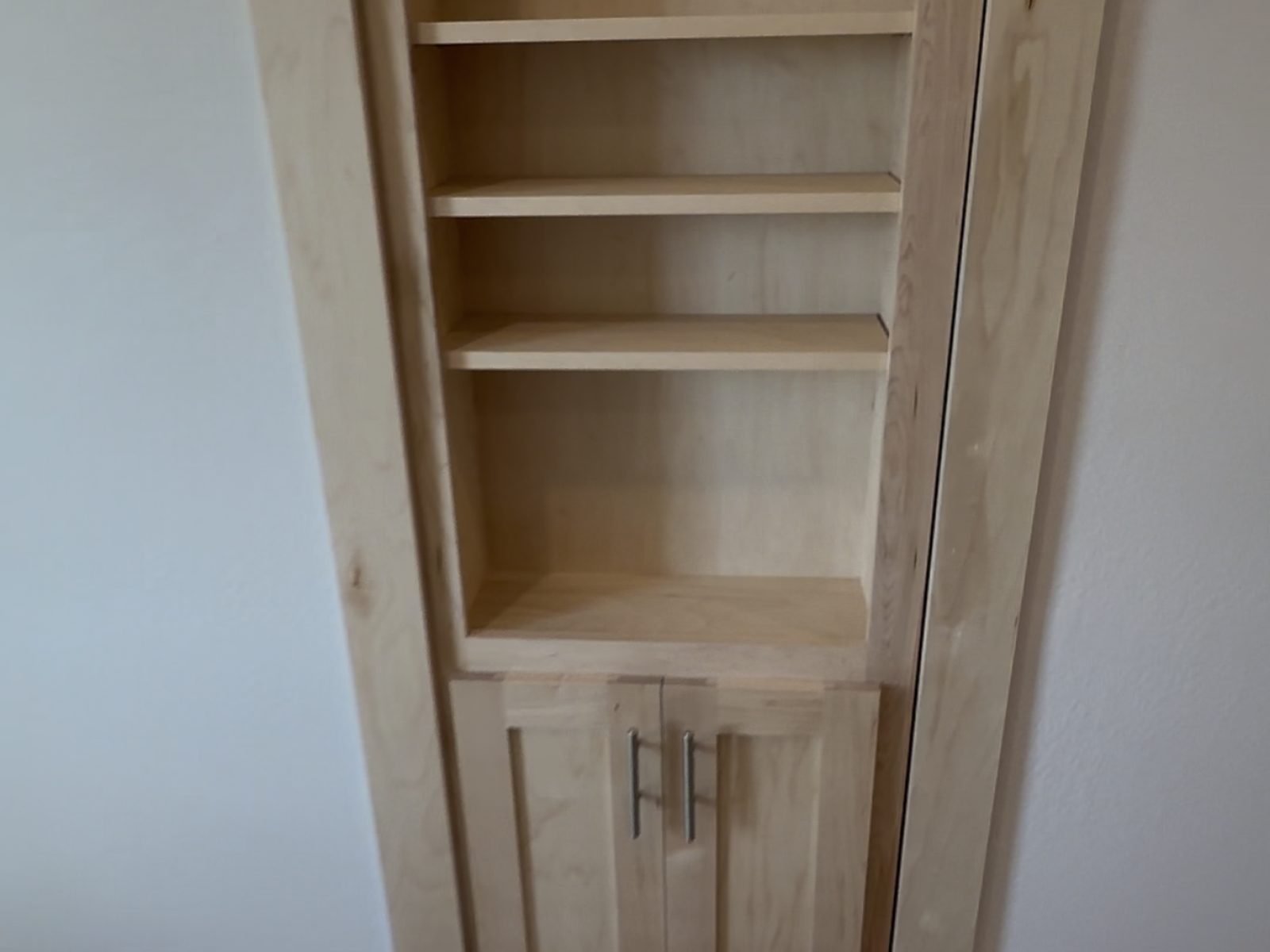 Light wood built-in bookshelves with cabinets in a converted attic room