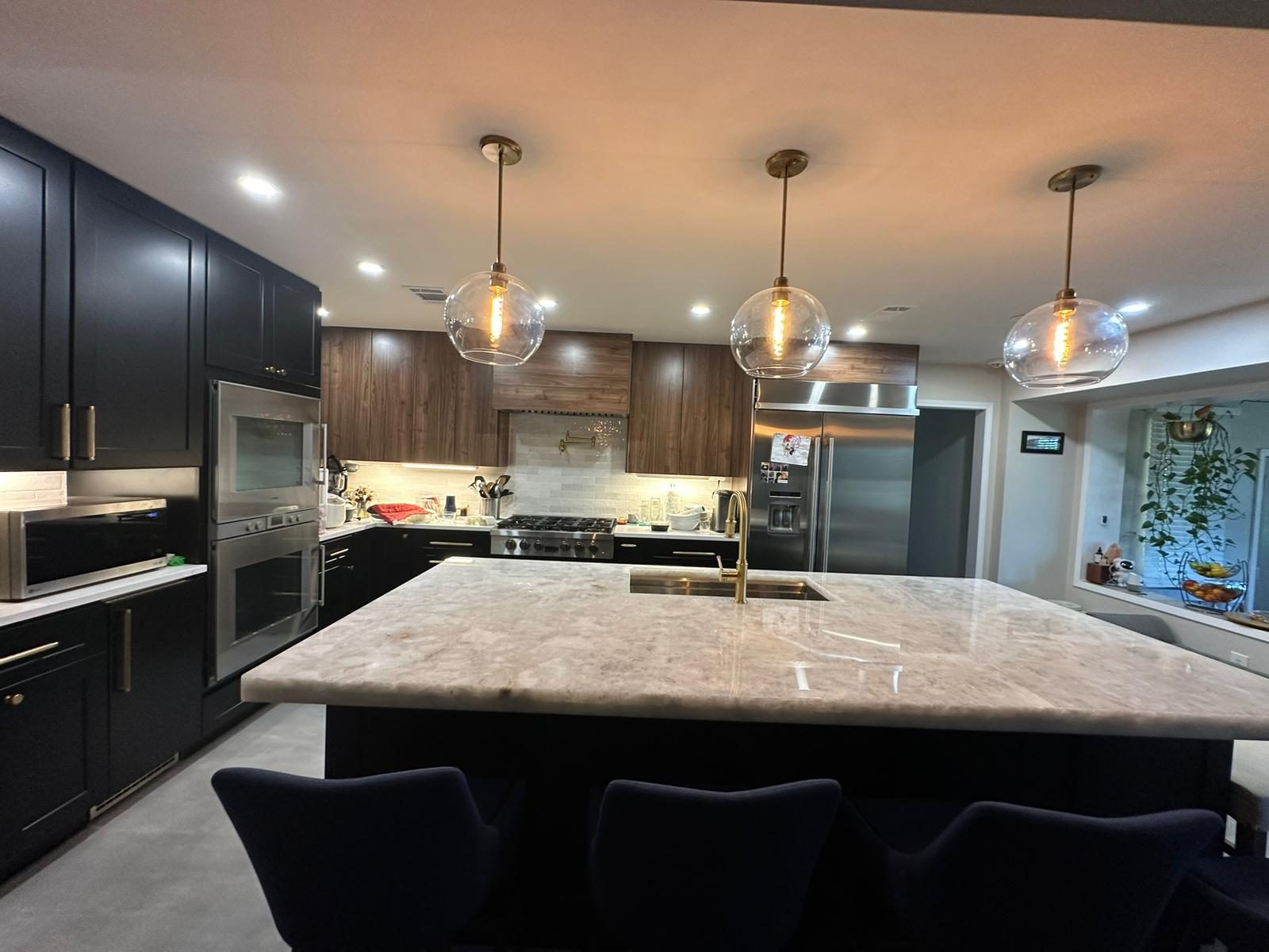Remodeled Austin kitchen with dark cabinets, wood accents, a marble island and pendant lighting